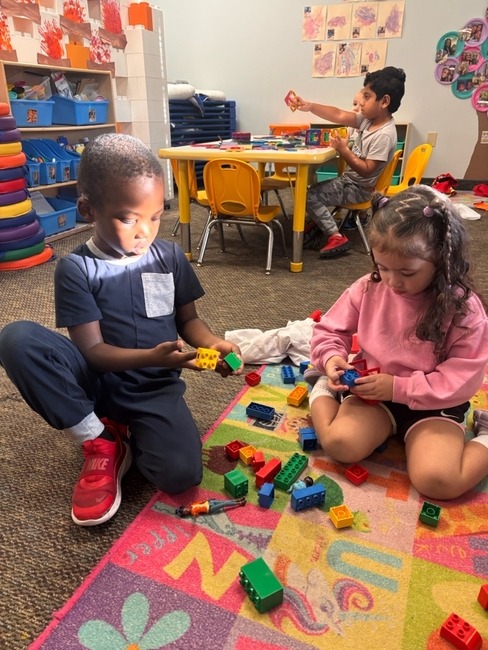Two children building with blocks on a colorful rug