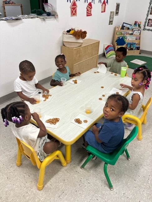 Children sharing a pretzel snack at the table