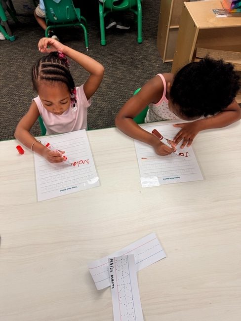 Two girls practicing writing their names