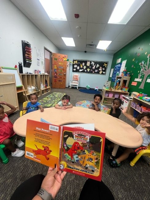 Children gathered at the table for story time with a Clifford book