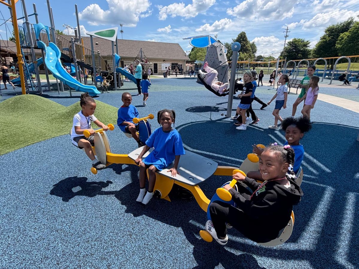 Smiling children riding a seesaw at the park
