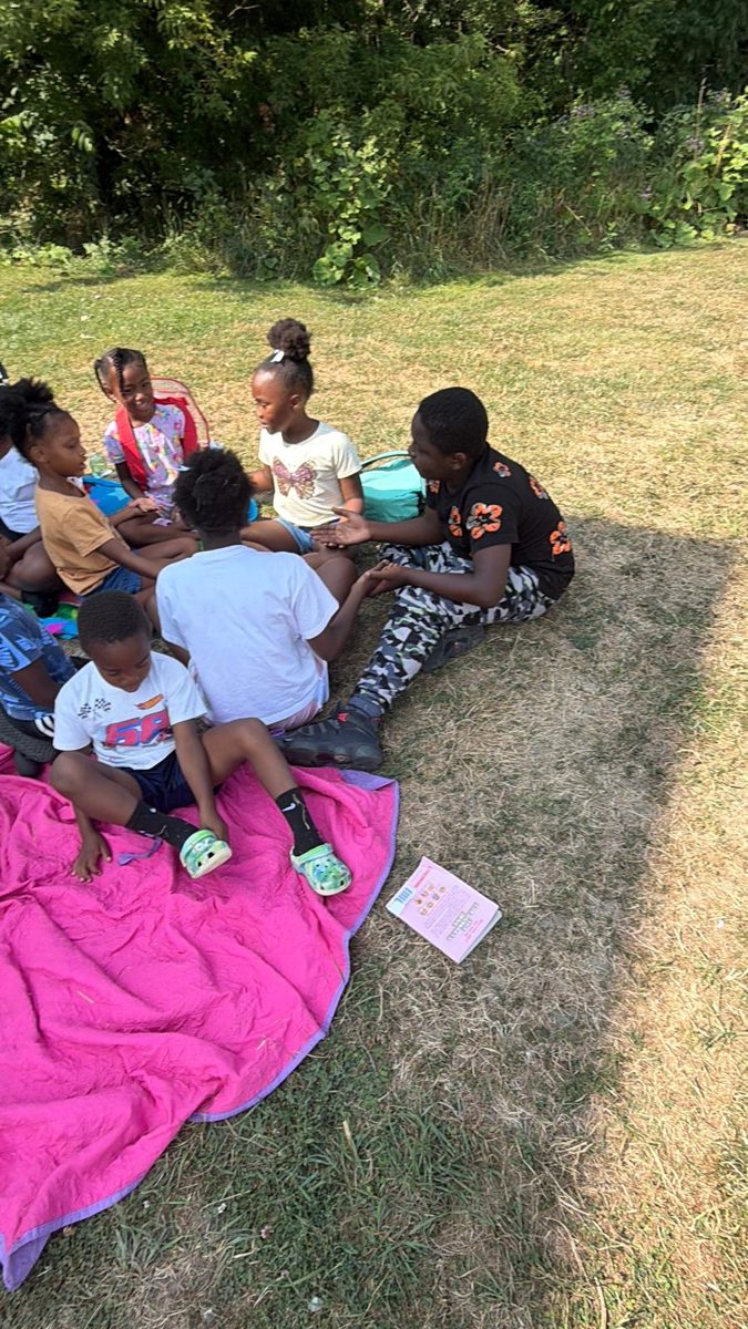 Children sitting in a circle on a blanket outdoors