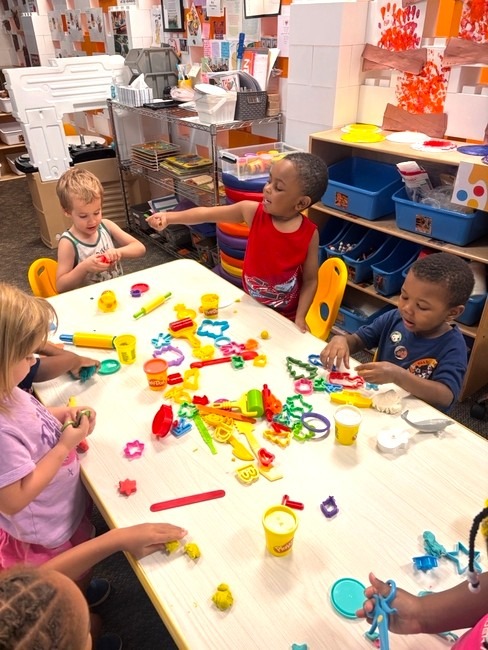 Children playing with play dough at a classroom table
