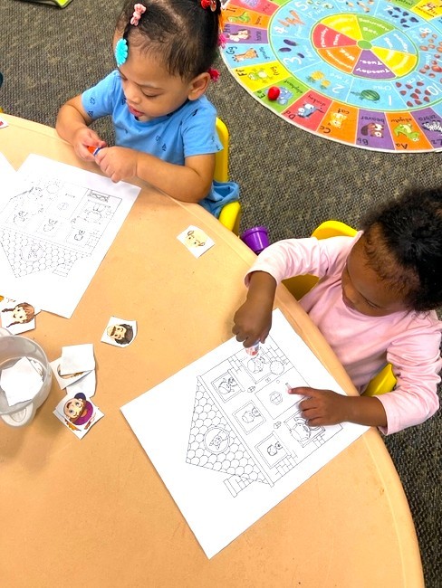 Two children working on a drawing activity at a table